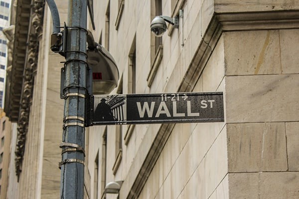 Wall Street road sign in front of a large buff brick building