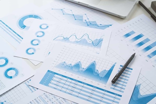 Printed financial performance charts scattered across a desk